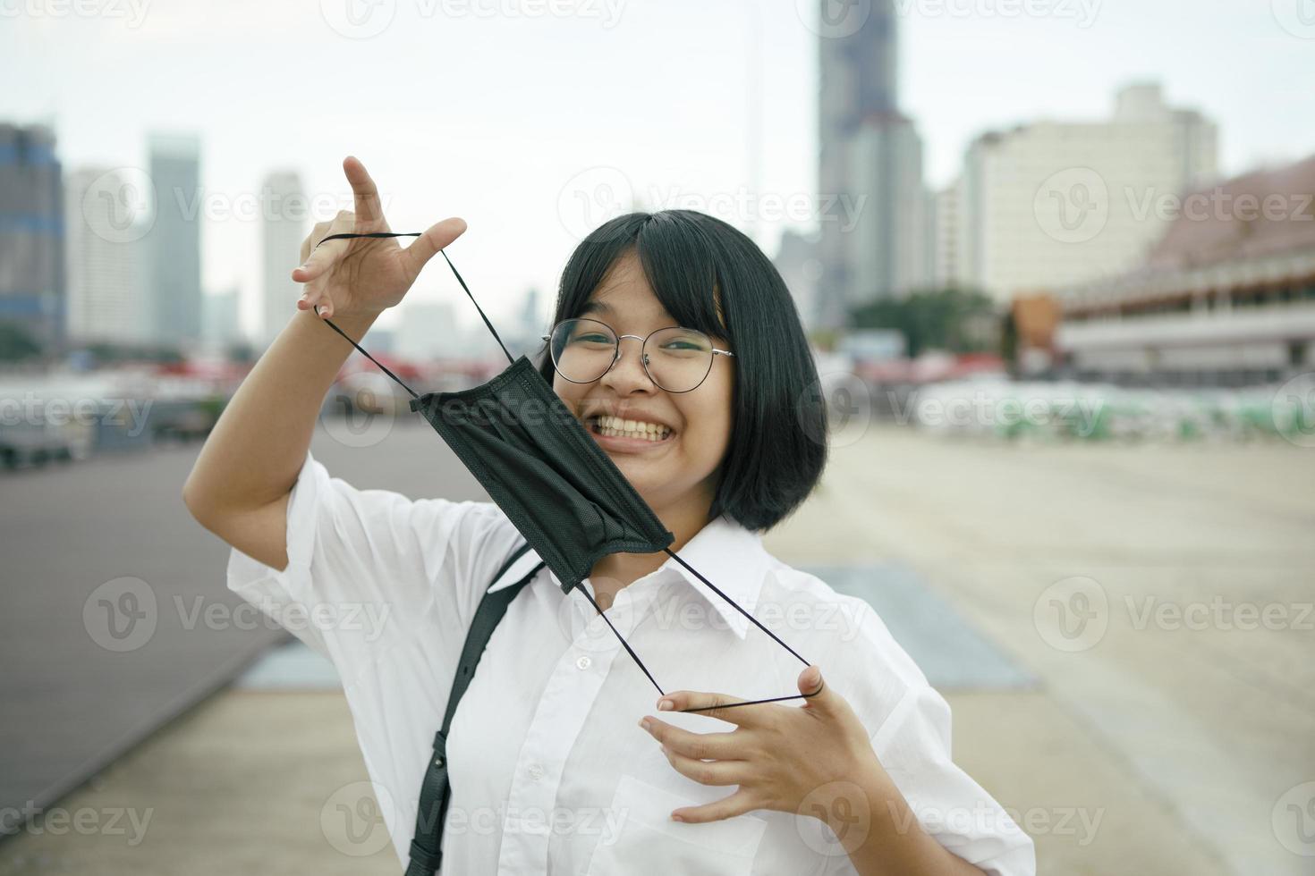 Alegre adolescente asiático con mascarilla de protección en la mano foto