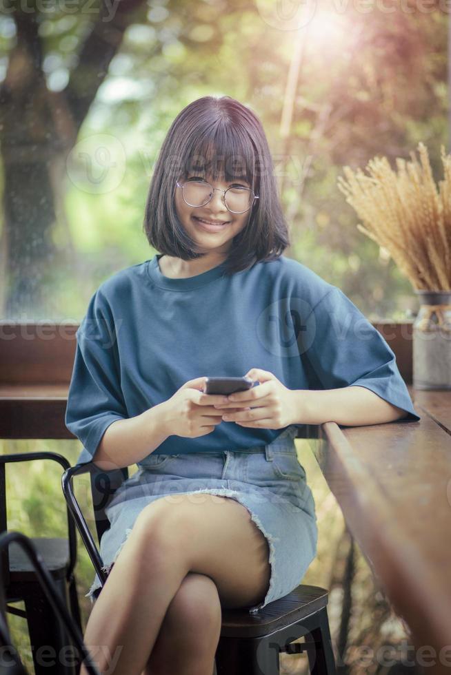 Adolescente asiático sosteniendo un teléfono inteligente en la mano sonriendo con felicidad foto