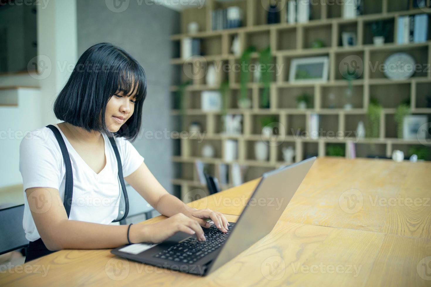 asian teenager working on laptop computer in home living room photo