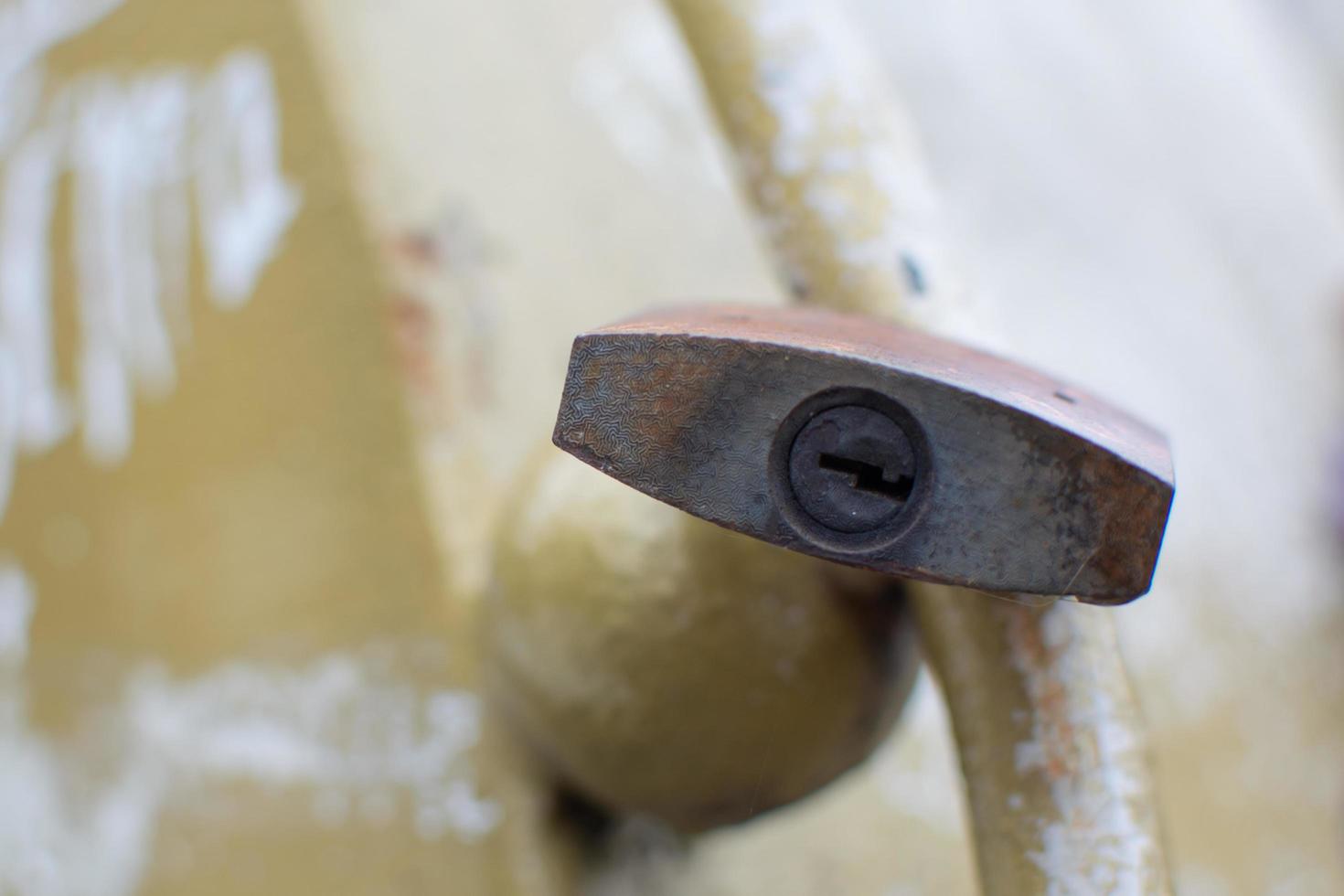 Keyhole of a padlock hanging from a railing. photo