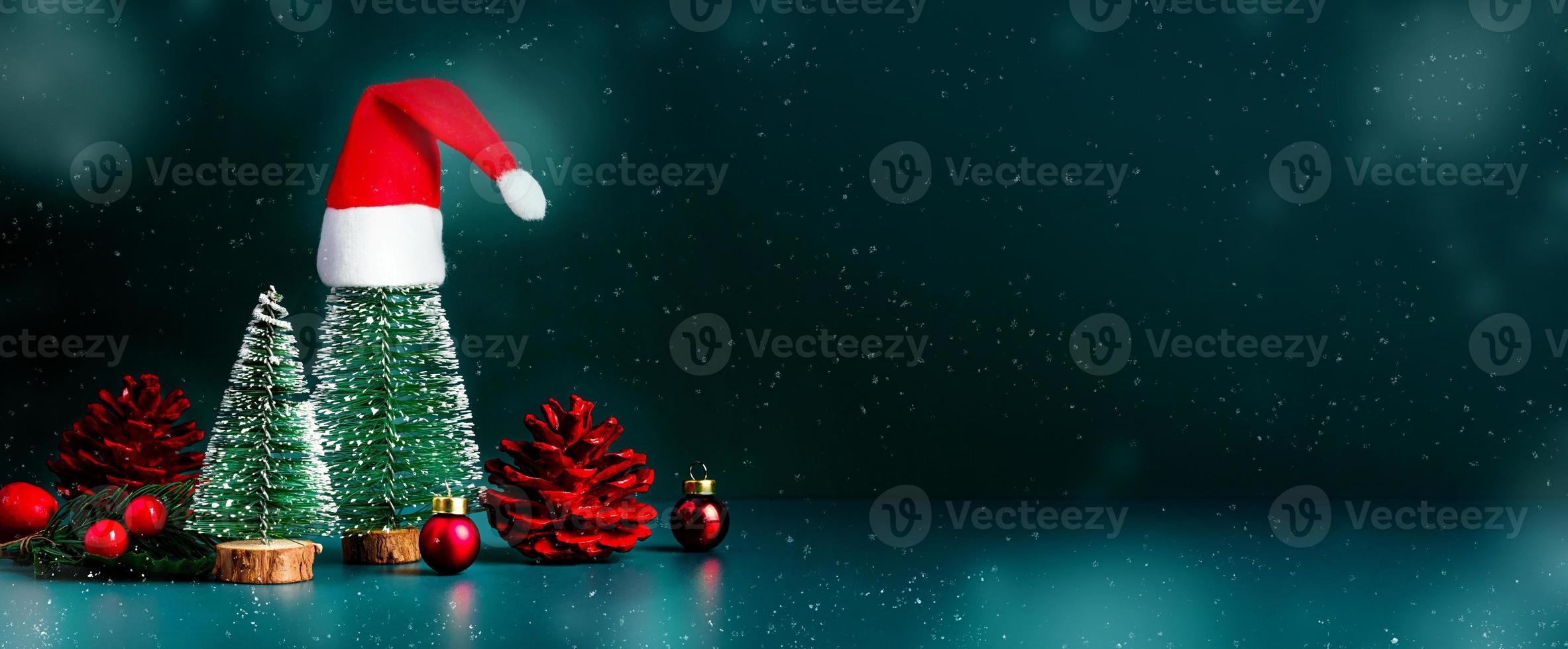 feliz navidad y próspero año nuevo nieve cayendo con árbol de navidad y sombrero rojo de santa claus sobre fondo verde oscuro espacio de maqueta de banner para mostrar el producto o diseño o texto foto