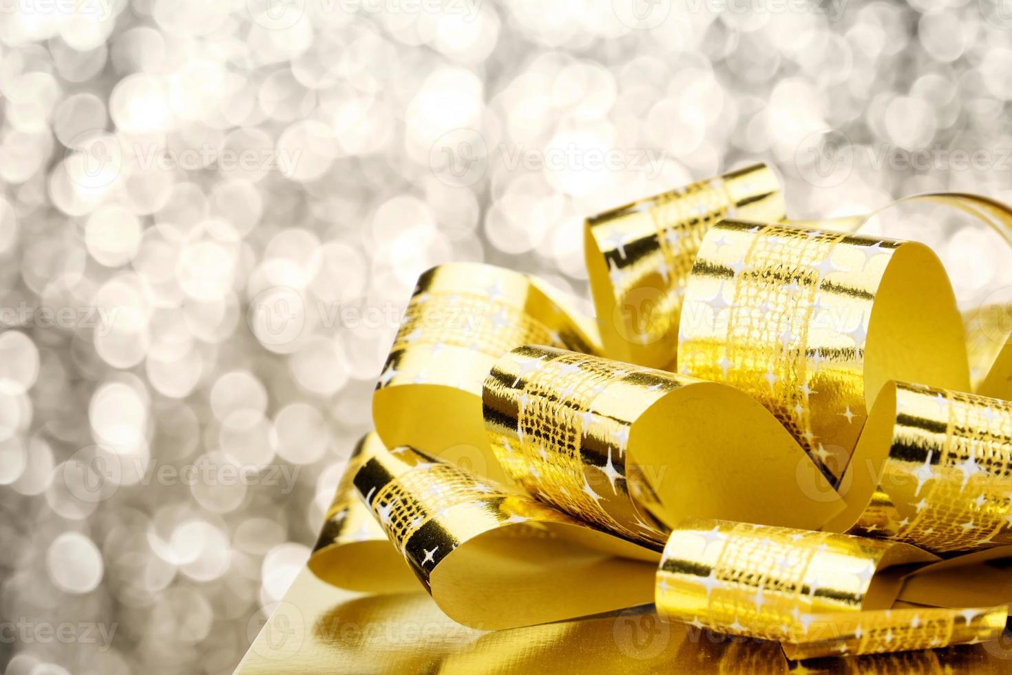 Close up Golden present box with big bow at bokeh white blur background photo