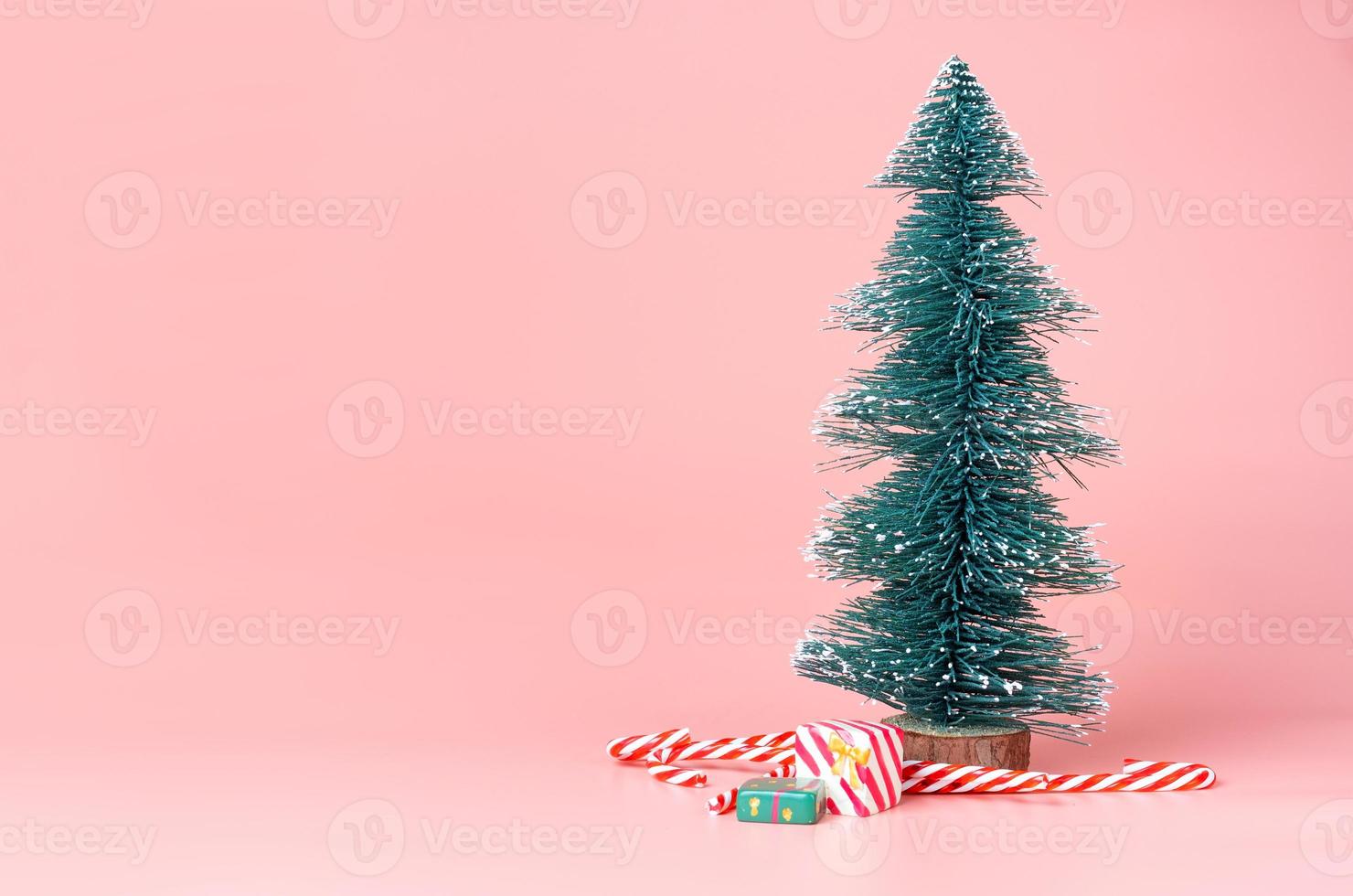 ree Christmas tree with candy cane on pastel pink studio background photo