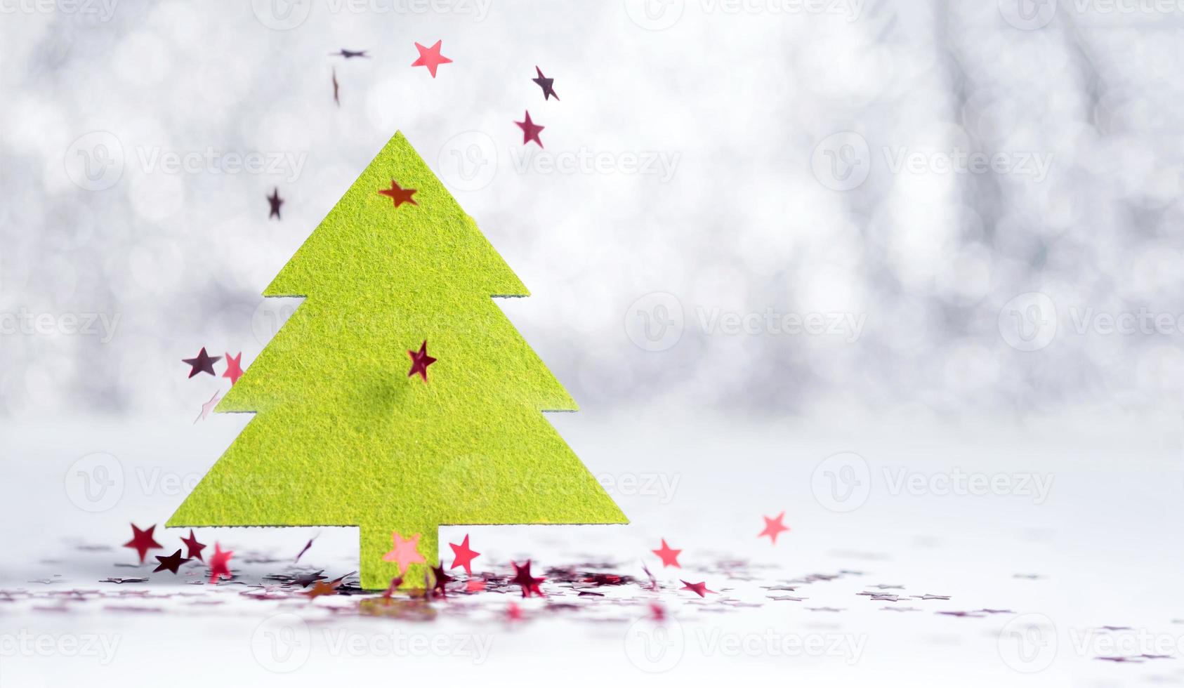 Close up green Christmas tree with sparkling red star falling on white photo