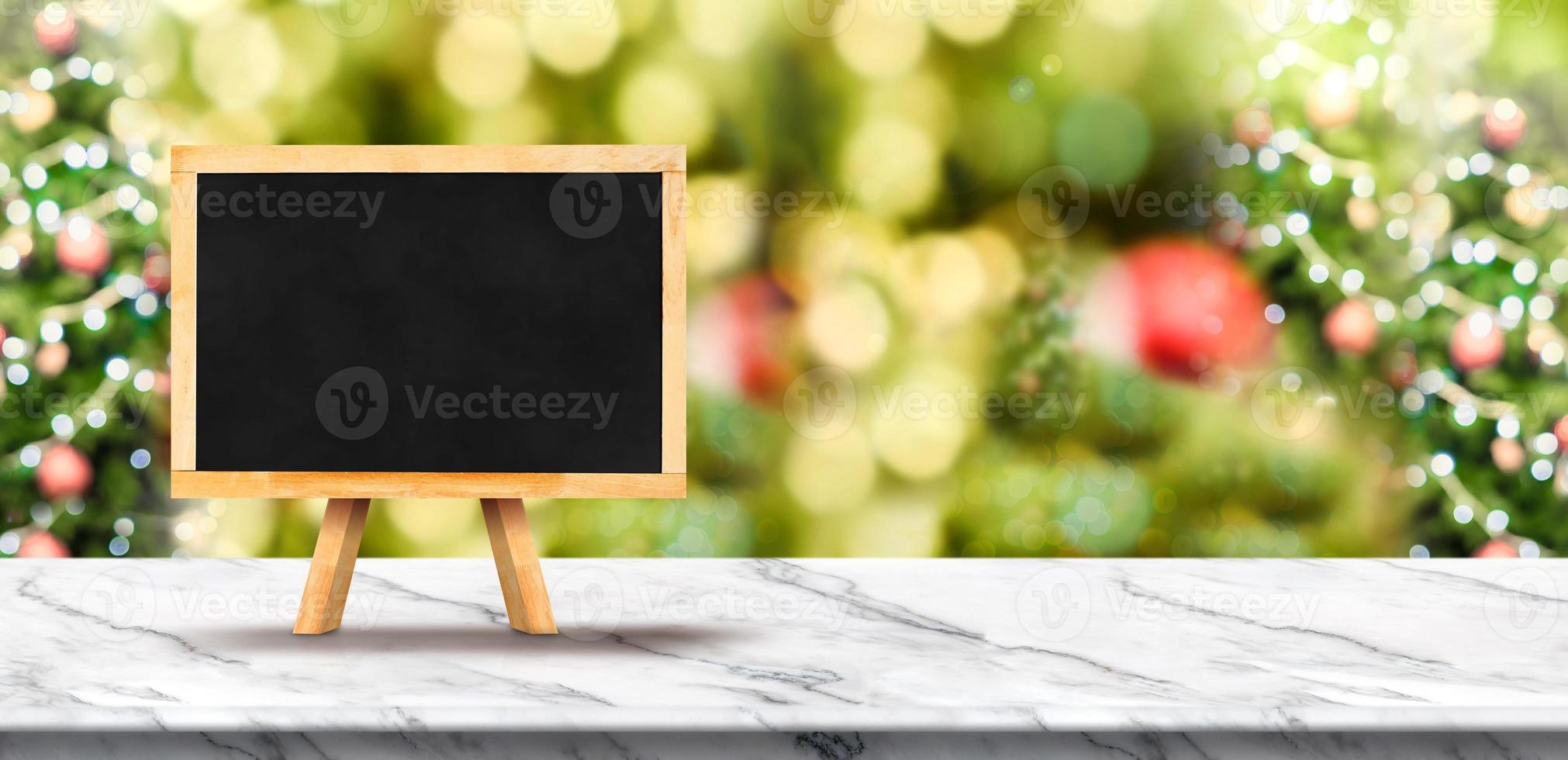 Blank blackboard on white marble table top with christmas tree photo