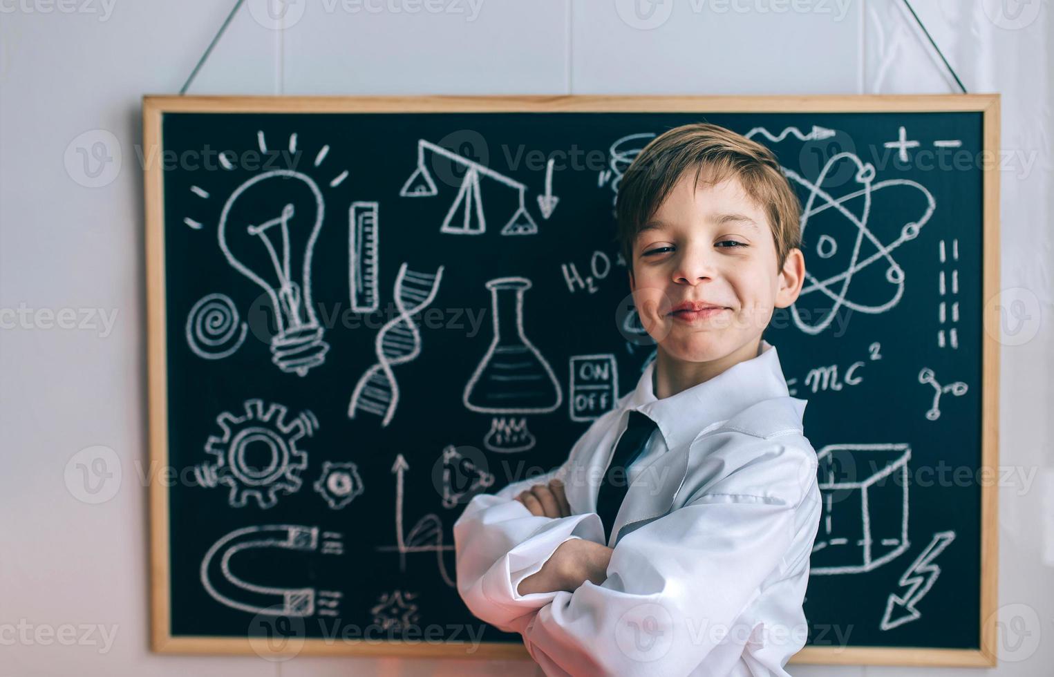 Smiling kid looking at camera in front of blackboard photo