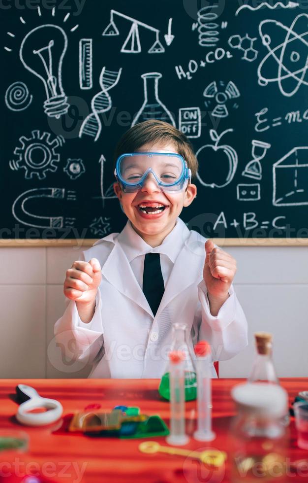 Happy kid with glasses laughing behind of experiments table photo