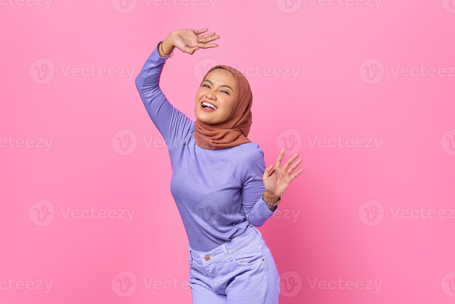 Portrait of beautiful young Asian woman dancing happy and cheerful on pink background photo