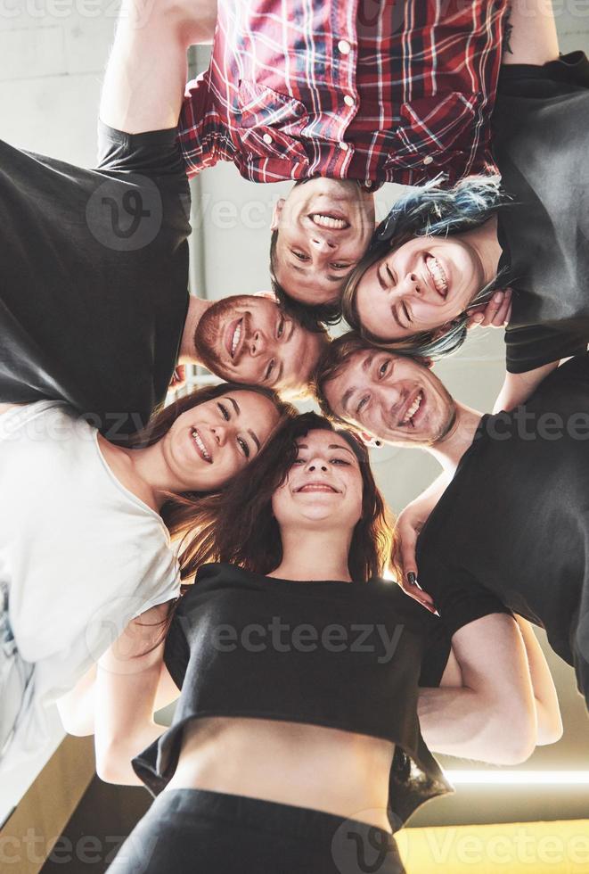 un gran grupo de amigos sonrientes abrazándose juntos. foto