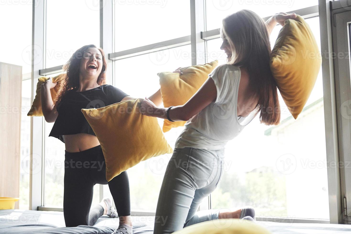 Merry happy girlfriends are fighting with pillows. photo