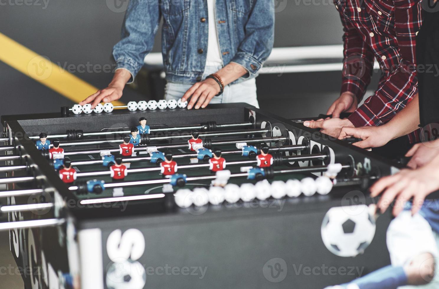 Smiling young people playing table football while on vacation photo