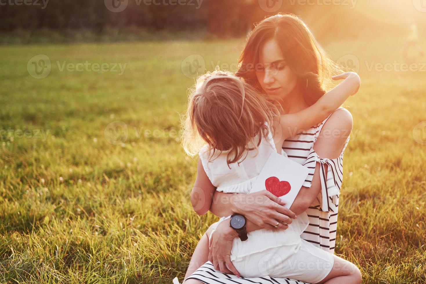 The child's daughter congratulates her mother and gives her a postcard. Mother and girl smile and hug. photo