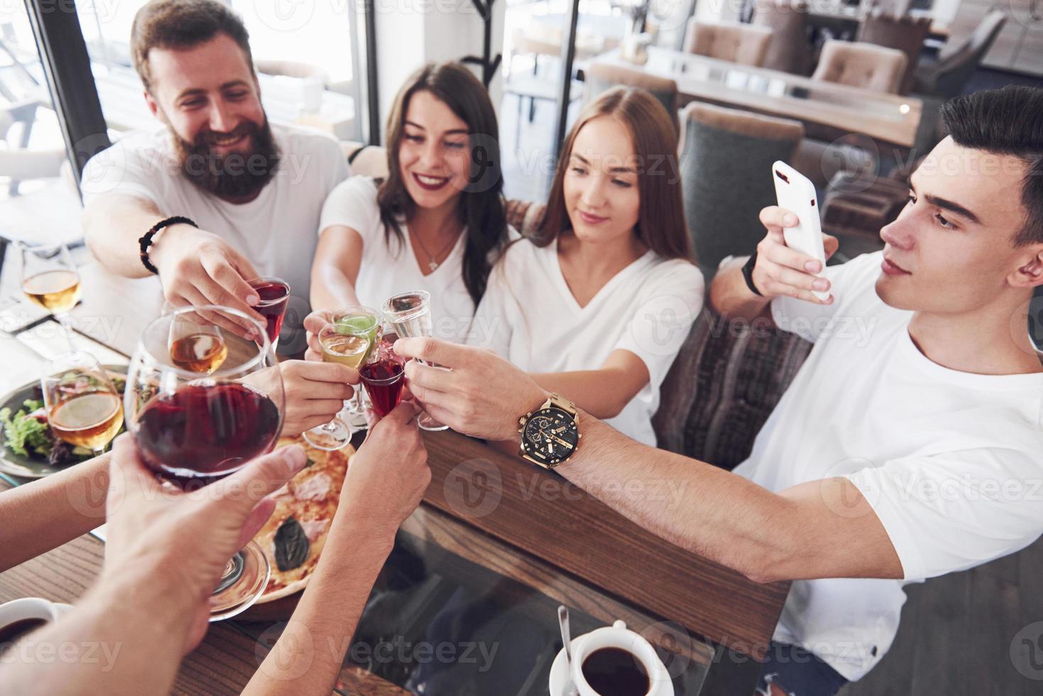 Friends got together by table with delicious food with glasses of red wine to celebrate a special occasion photo