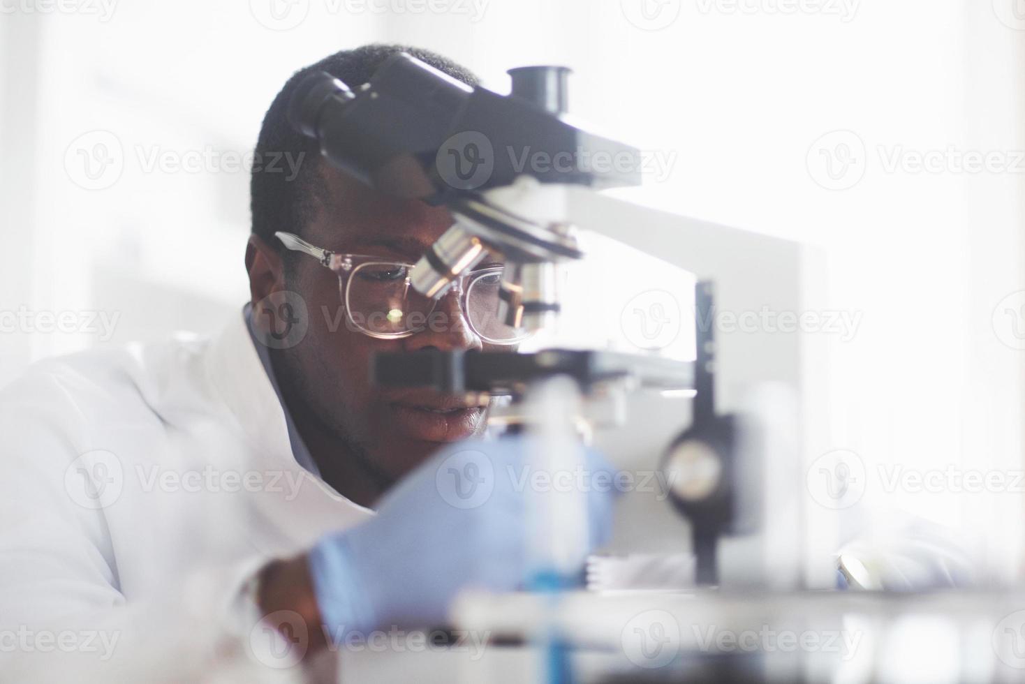 The scientist works with a microscope in a laboratory conducting experiments and formulas. photo