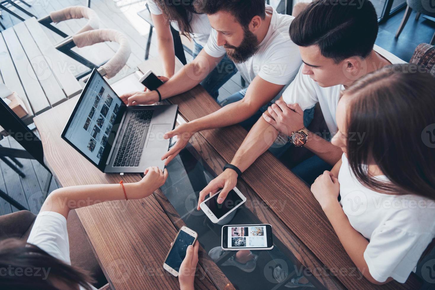 un grupo de jóvenes con gadgets y una computadora portátil organizan una lluvia de ideas y se comunican entre sí. el concepto de desarrollar una empresa joven foto