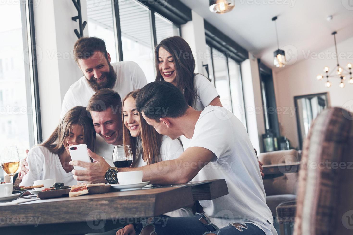 un grupo de personas hace una foto selfie en un café. los mejores amigos se reunieron en una mesa para cenar comiendo pizza y cantando varias bebidas