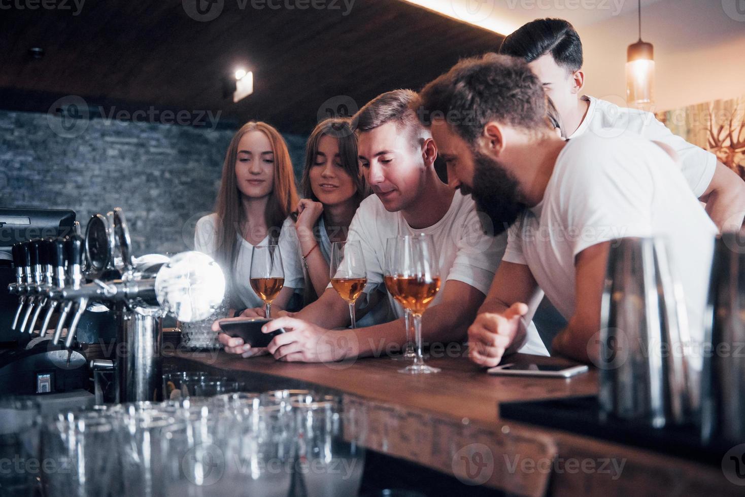 concepto de ocio y comunicación. Grupo de amigos sonrientes felices disfrutando de bebidas y hablando en el bar o pub foto