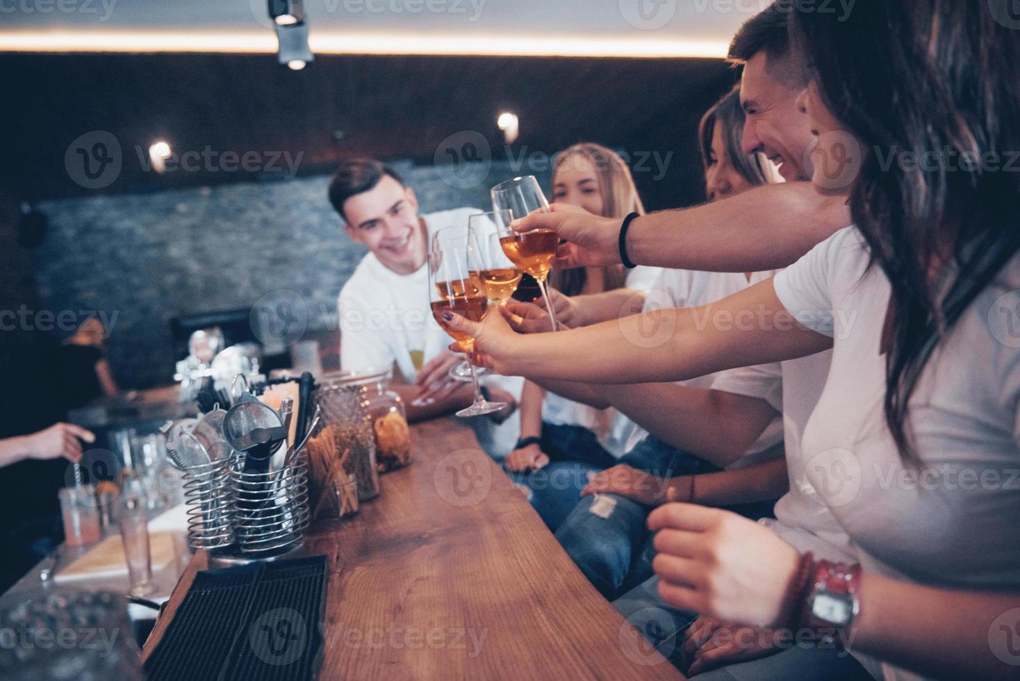 concepto de ocio y comunicación. Grupo de amigos sonrientes felices disfrutando de bebidas y hablando en el bar o pub foto