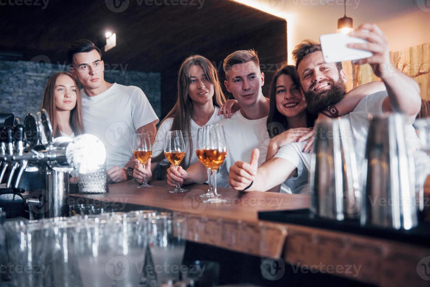 concepto de ocio y comunicación. Grupo de amigos sonrientes felices disfrutando de bebidas y hablando en el bar o pub foto