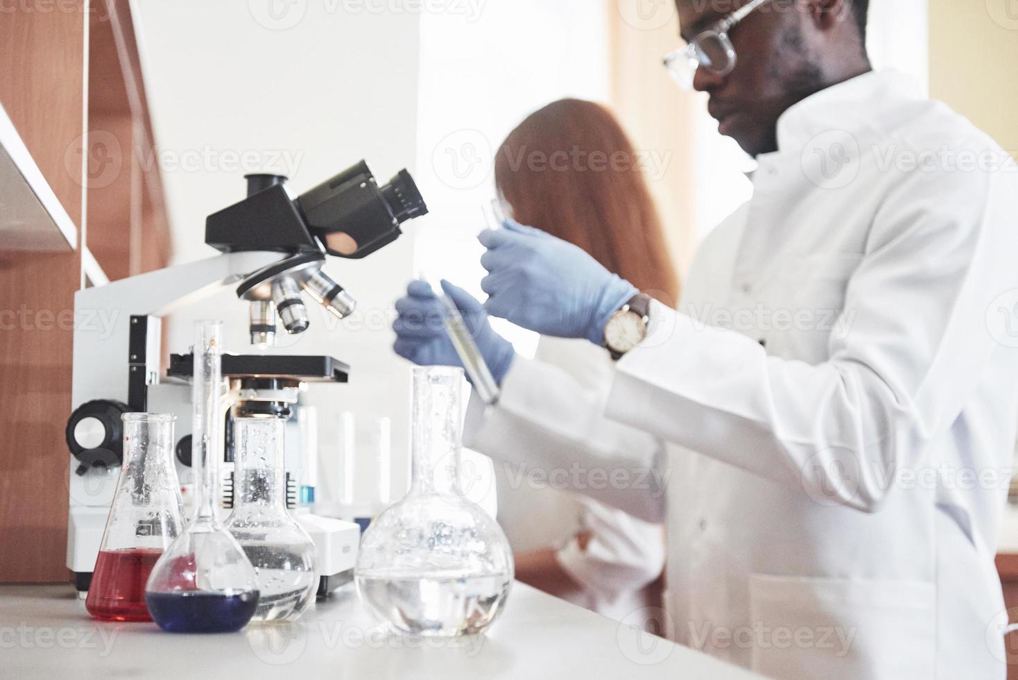 Los laboratorios de laboratorio realizan experimentos en un laboratorio químico en matraces transparentes. fórmulas de salida foto