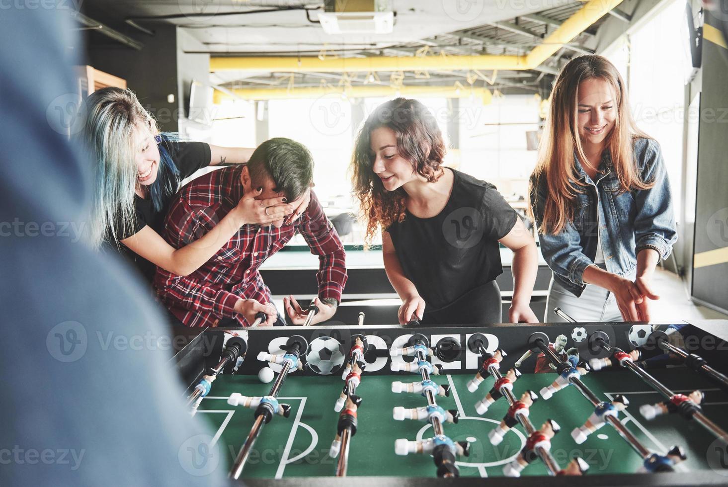 Smiling young people playing table football while indoors photo