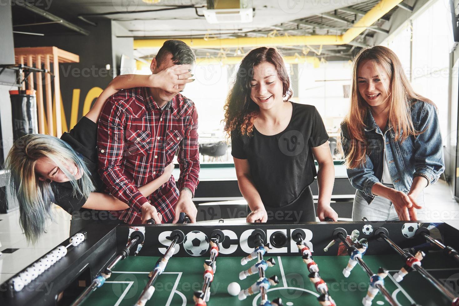 jóvenes sonrientes jugando al futbolín en el interior foto