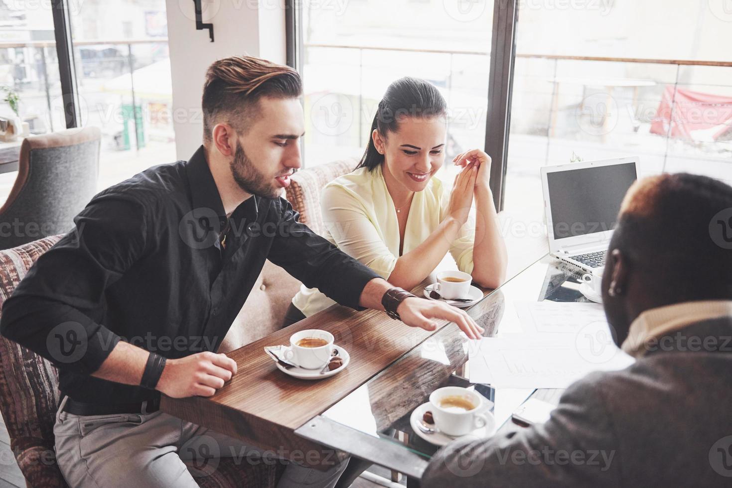 empresario de pueblo multiétnico, concepto de pequeña empresa. Mujer mostrando algo a sus compañeros de trabajo en la computadora portátil mientras se reúnen alrededor de una mesa de conferencias foto