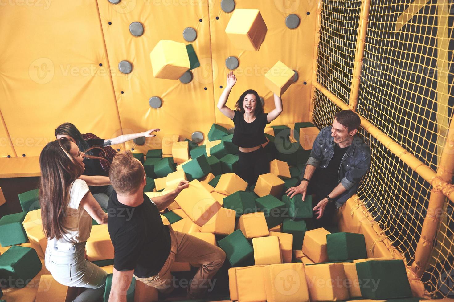 The company is a young woman who has fun with soft blocks on a children's playground in a trampoline center. photo