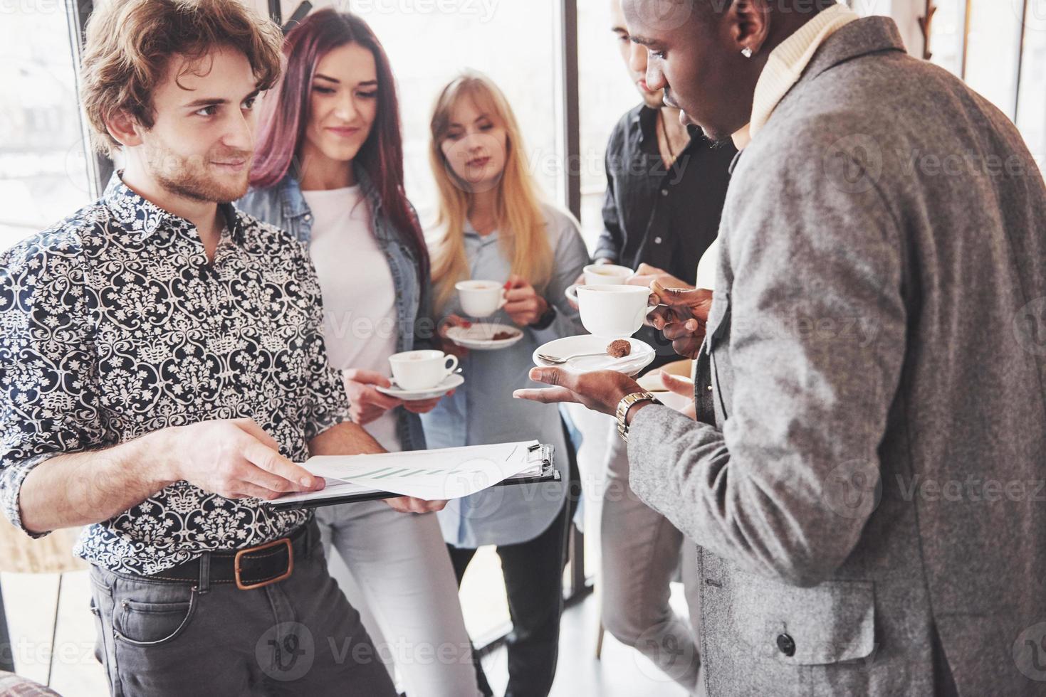 Successful business people are using gadgets, talking and smiling during the coffee break in office photo