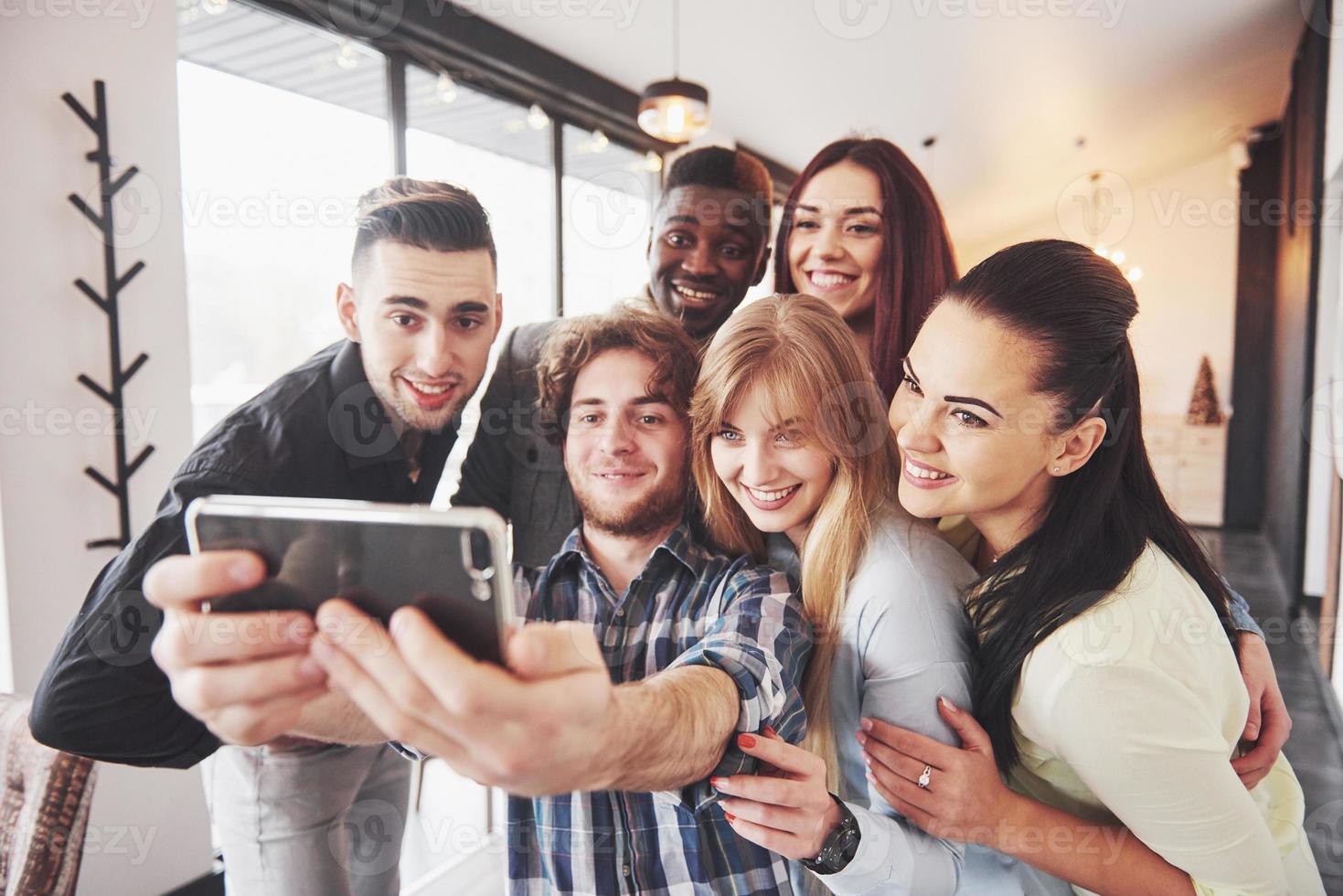 Self portrait of mixed race unity of african, american, asian, caucasian friends, happy bearded men and beautiful women in red santa hat showing thumb up, like, ok gesture to the camera in office photo