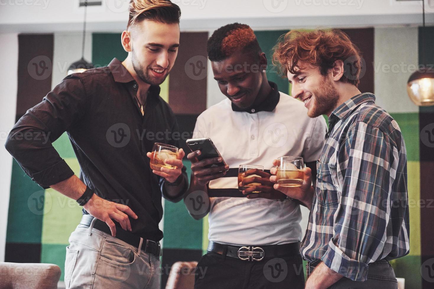 promising young multi ethnic people celebrating and drinking whiskey toast, watch gadget photo