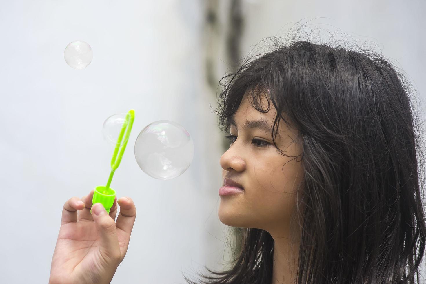 A girl holding a bubble maker and blowing them out. photo