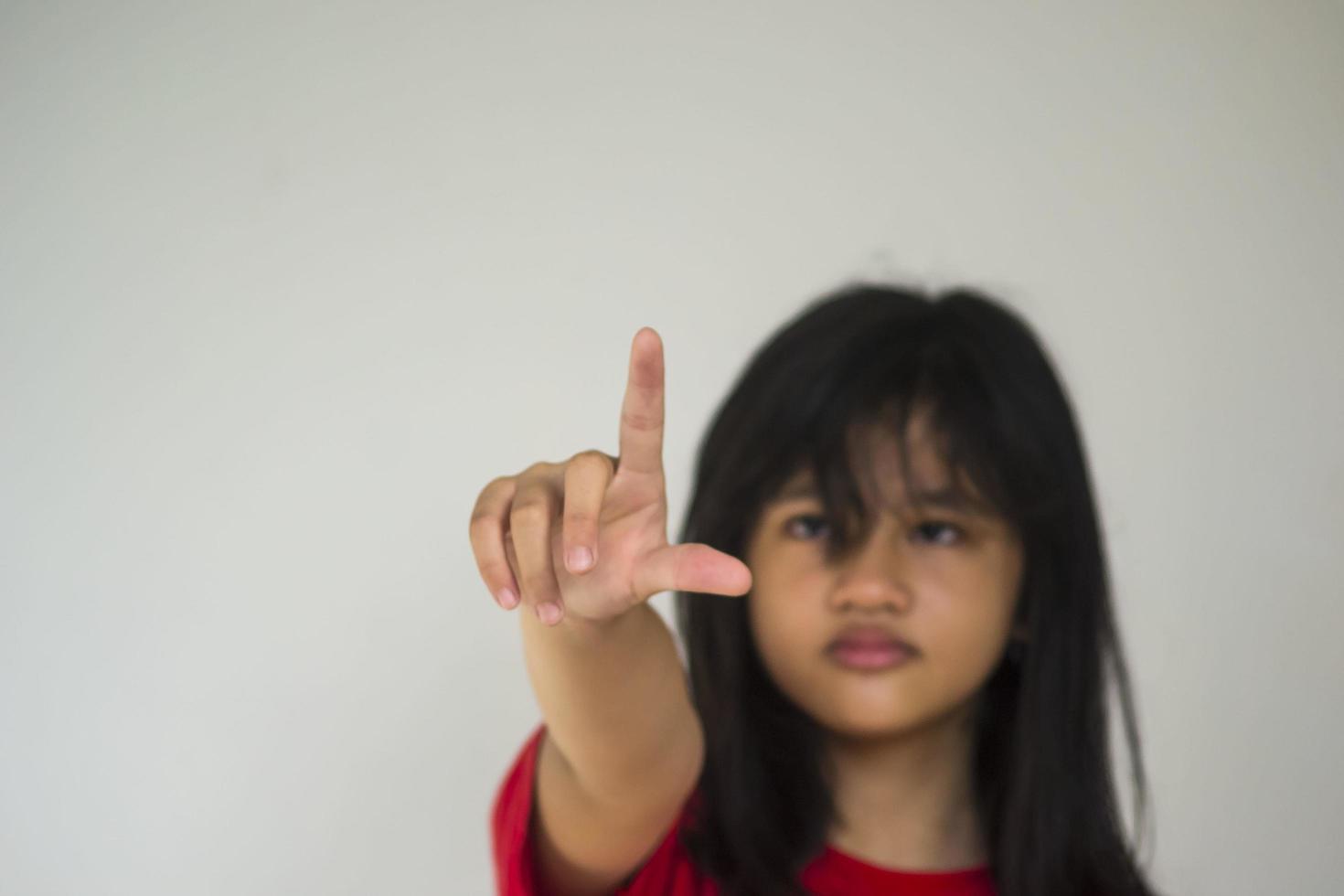 A beautiful young girl pinting with her index finger photo
