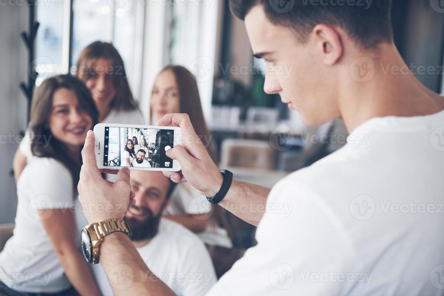 Blur portrait of blissful young best friends with hands holding phone on foreground photo