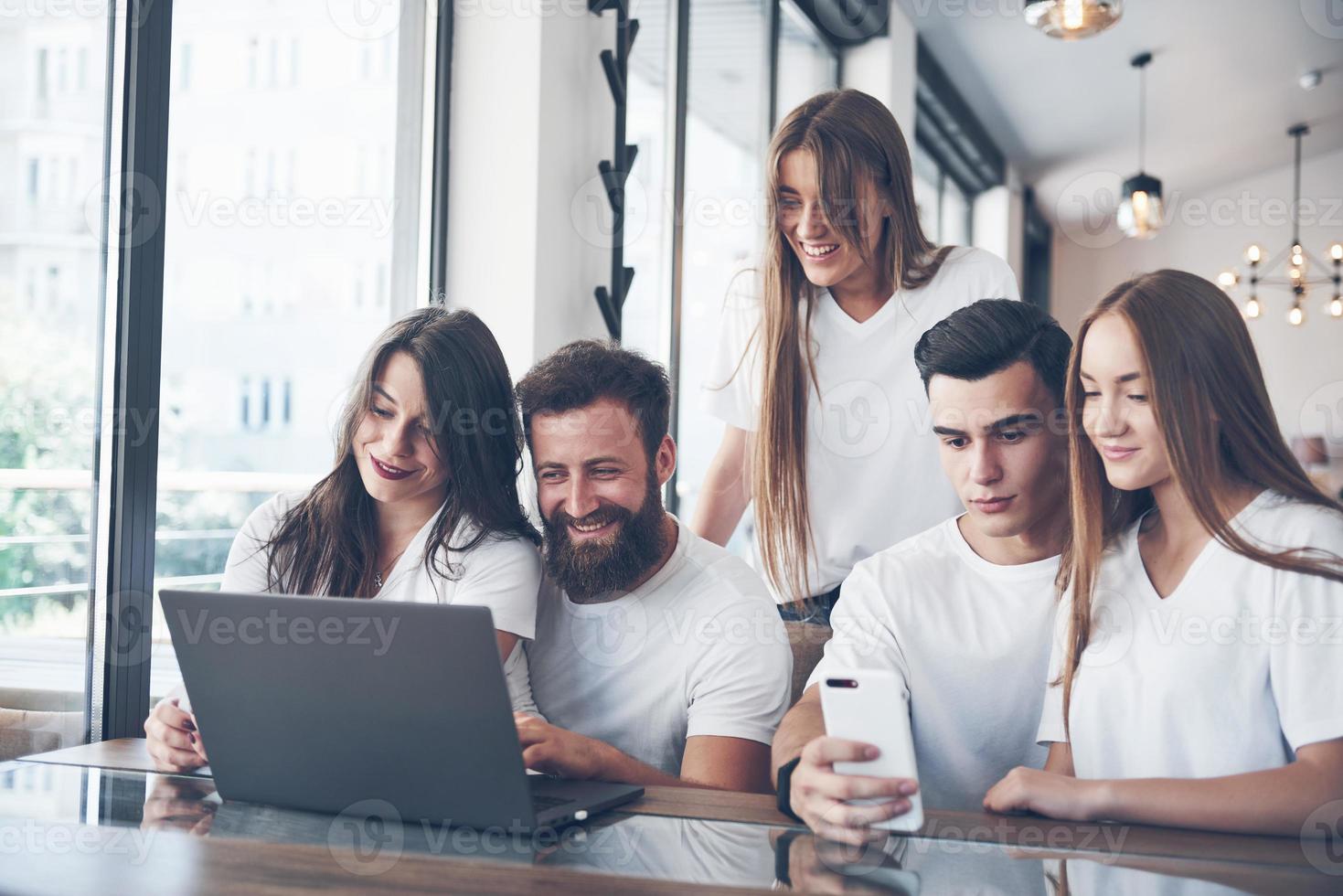 un grupo de jóvenes con gadgets y una computadora portátil organizan una lluvia de ideas y se comunican entre sí. el concepto de desarrollar una empresa joven foto