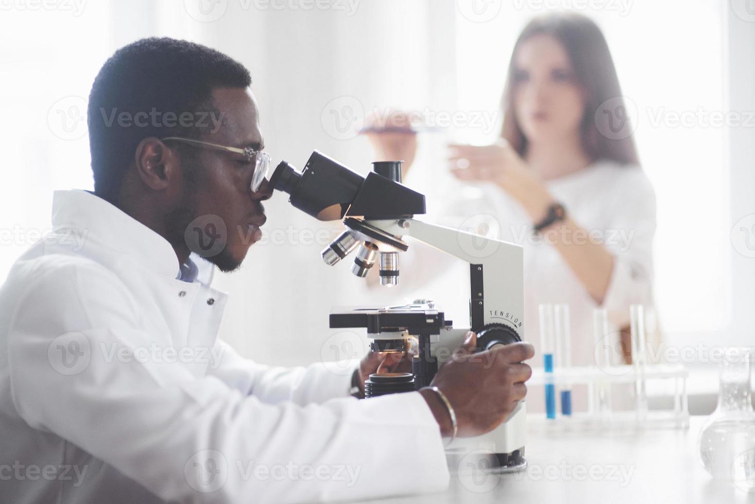 The scientist works with a microscope in a laboratory conducting experiments and formulas. photo