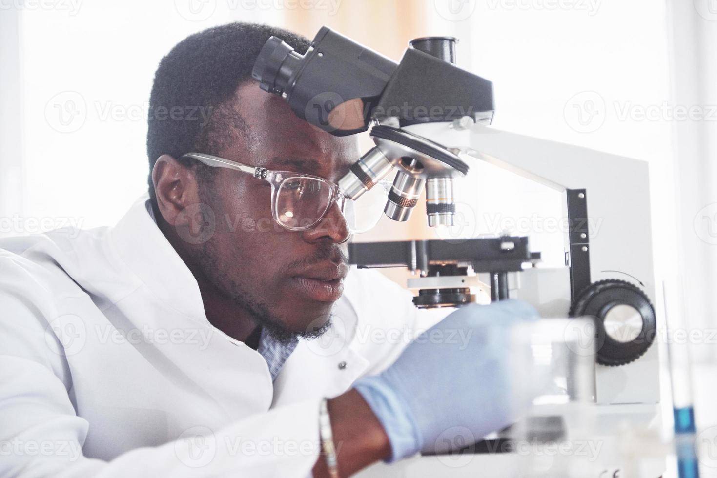 The scientist works with a microscope in a laboratory conducting experiments and formulas. photo