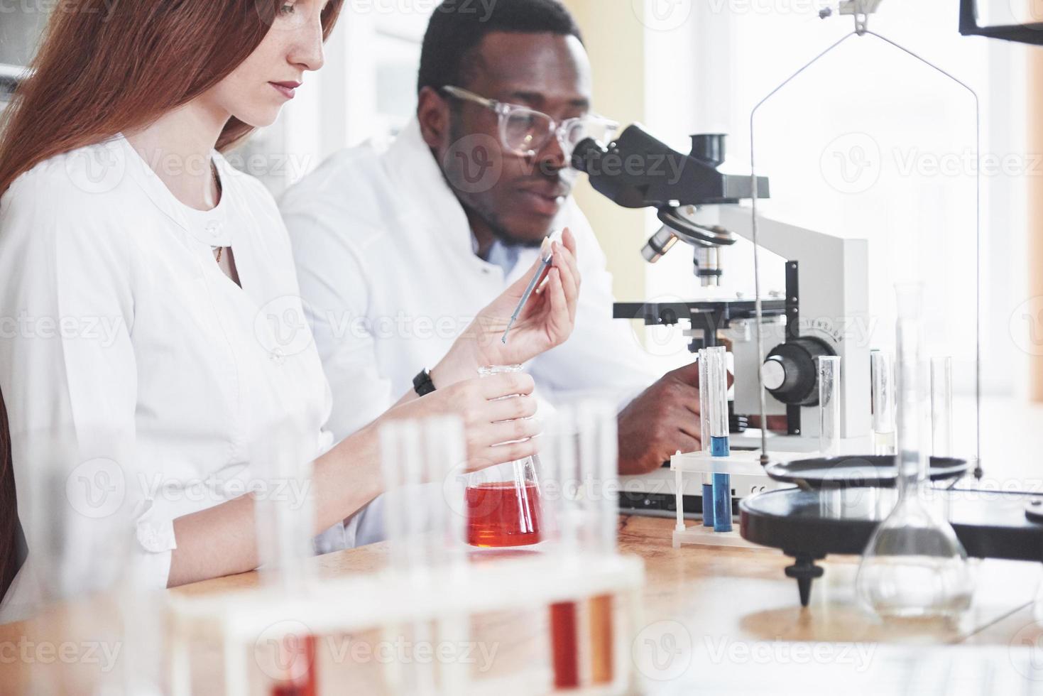 Los científicos trabajan en estrecha colaboración con el microscopio en el laboratorio mediante la realización de experimentos y análisis. foto