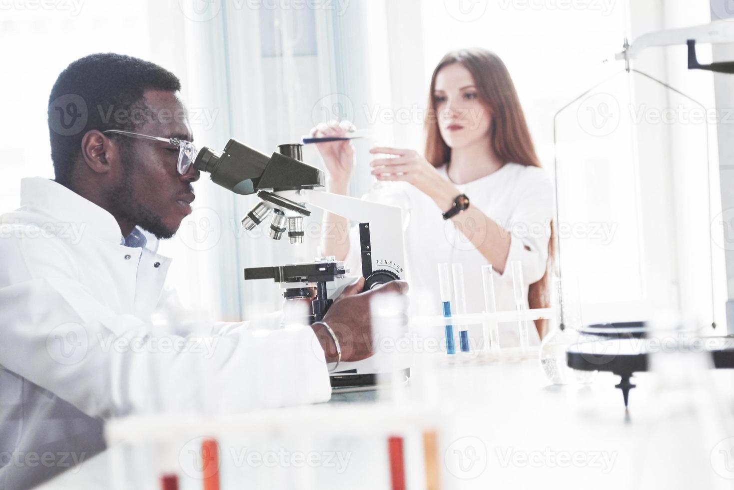 The scientist works with a microscope in a laboratory conducting experiments and formulas. photo