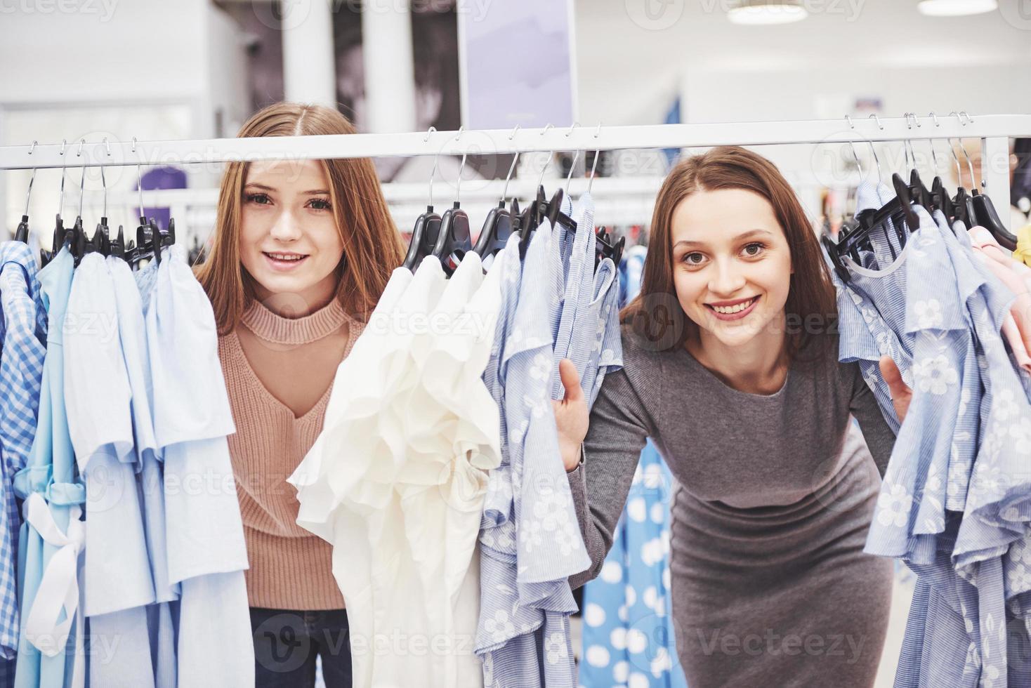 los mejores amigos pasan tiempo juntos. dos hermosas chicas hacen compras en la tienda de ropa. se vistieron con la misma ropa foto