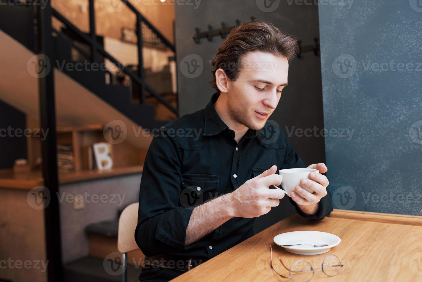 Apuesto hombre barbudo en camisa a cuadros sosteniendo tenedor comiendo en el café y sonriendo foto