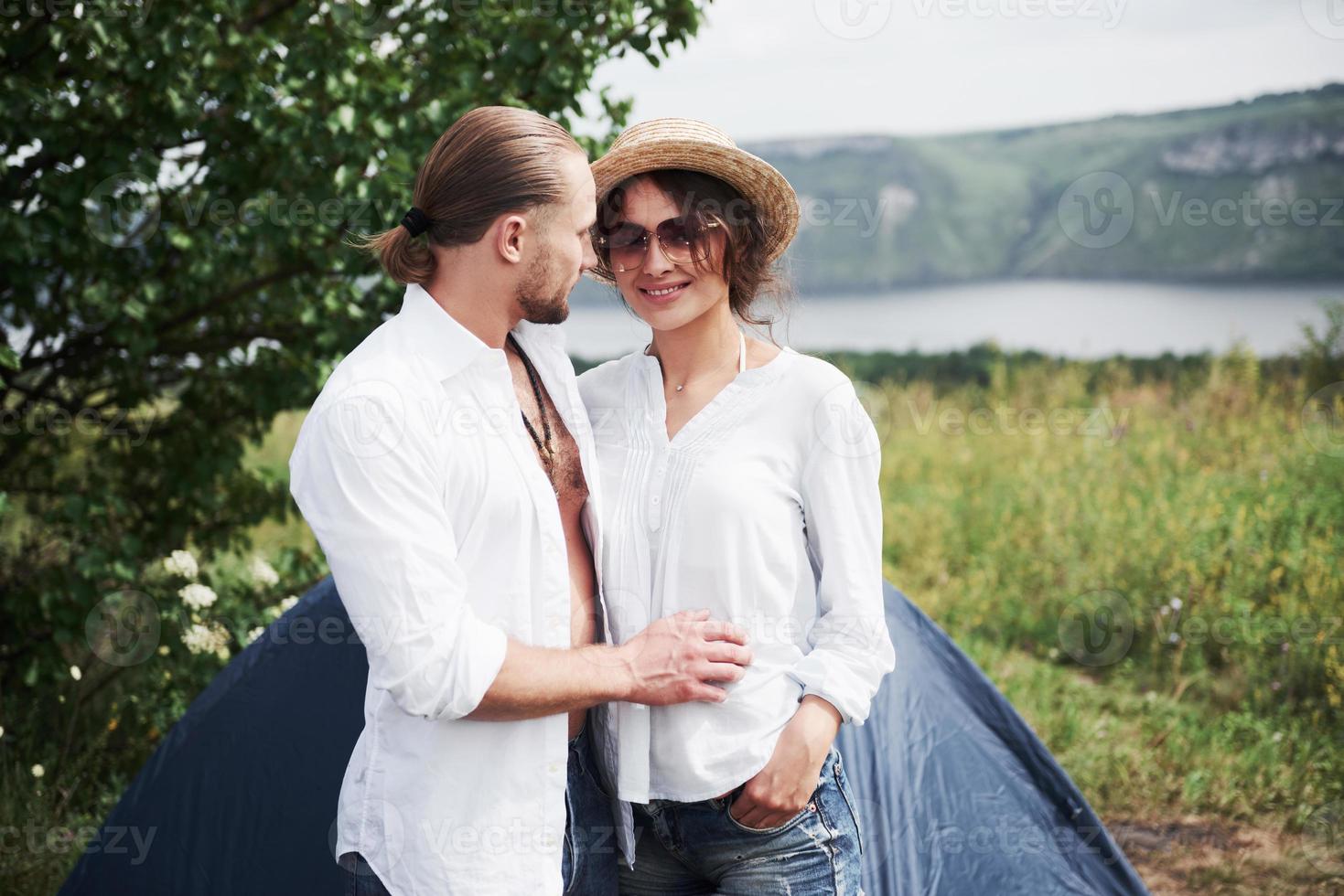 Portrait of young people, a guy and a girl, tourists who are standing near a tent and find themselves resting in nature photo