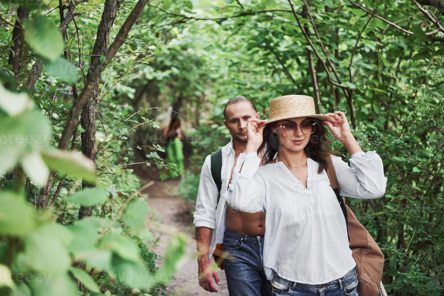 Two hikers with backpacks on the back in nature. Young couple man and woman like an active holiday with a tent, so they got out on the nature in a sunny day photo