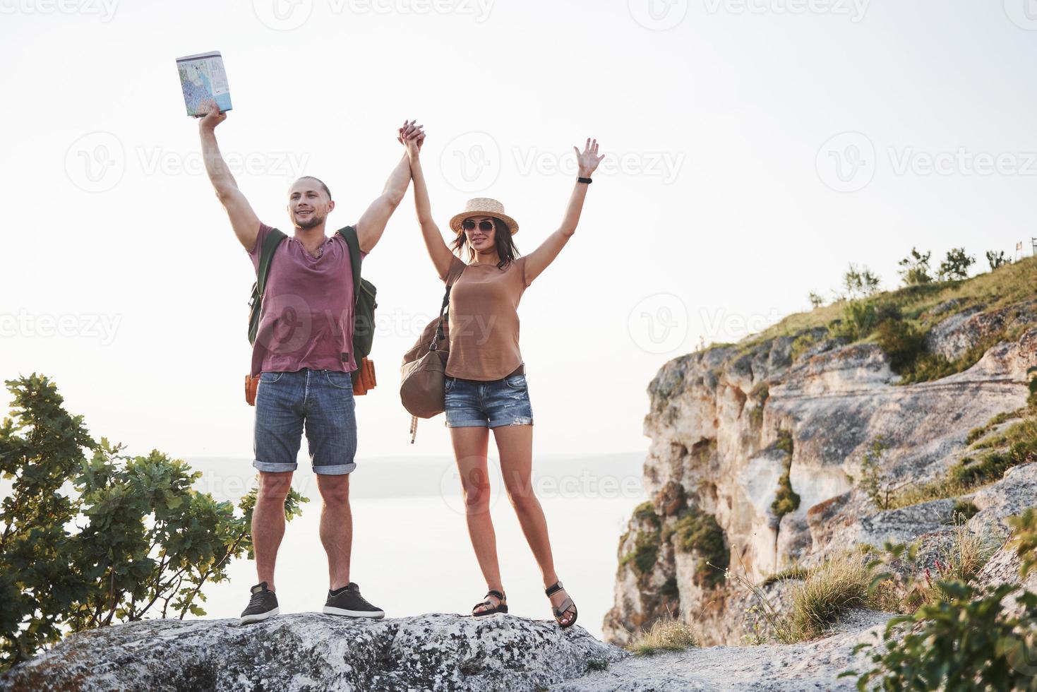 Two tourist male and woman with backpacks stand to the top of the mountain and enjoying sunrise. Travel lifestyle adventure vacations concept photo