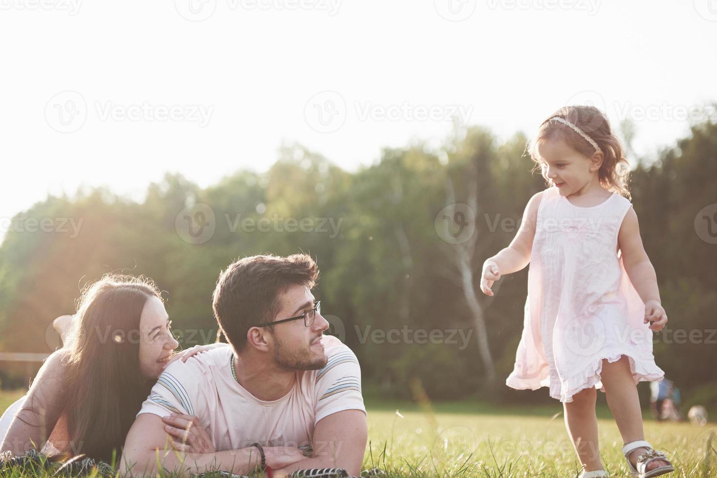 familia feliz, padre de madre e hija de bebé en la naturaleza al atardecer foto