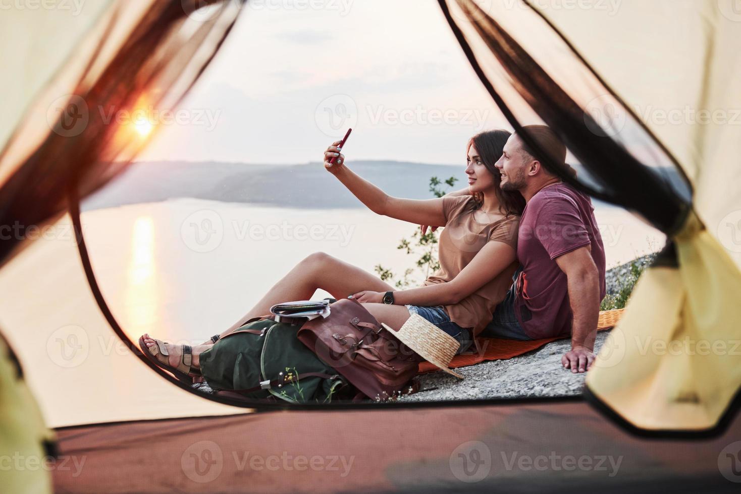 vista desde la tienda de la pareja acostada una vista del lago durante el viaje de senderismo. concepto de estilo de vida avel vacaciones de aventura al aire libre foto