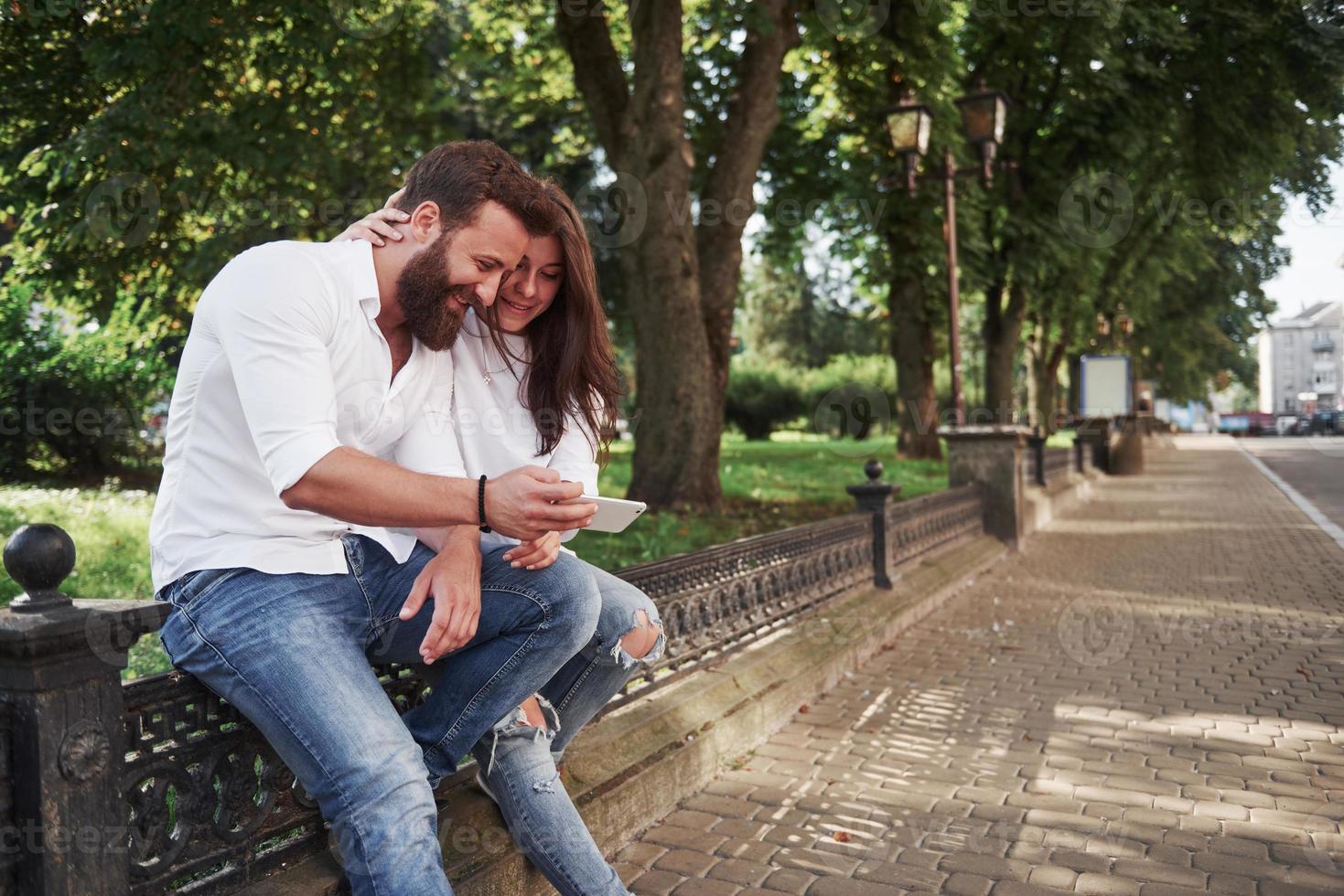 Young couple looking at a smartphone on a sunny day in the city photo
