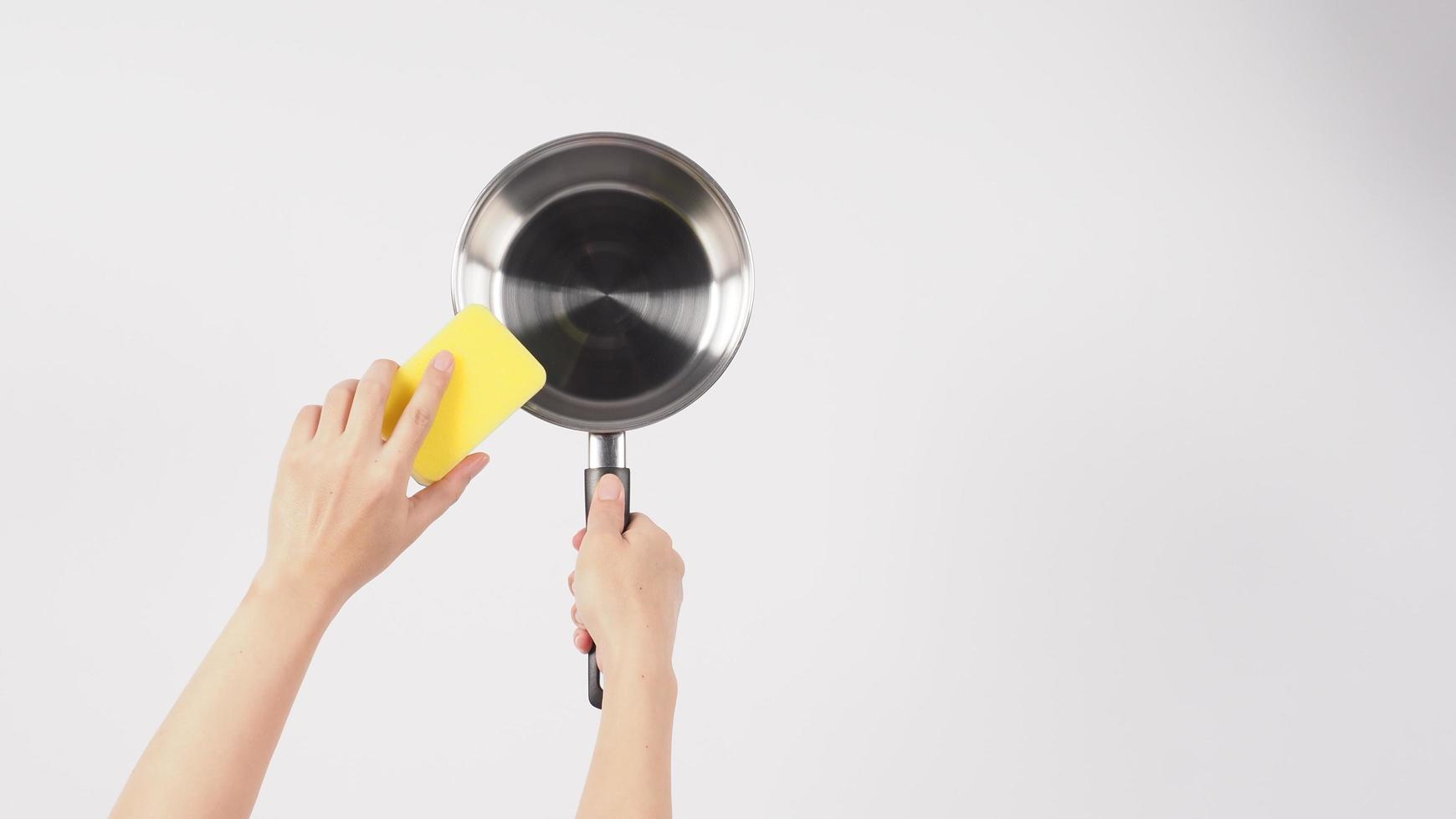 Pot cleaning. Man hand on white background cleaning the non stick pot photo