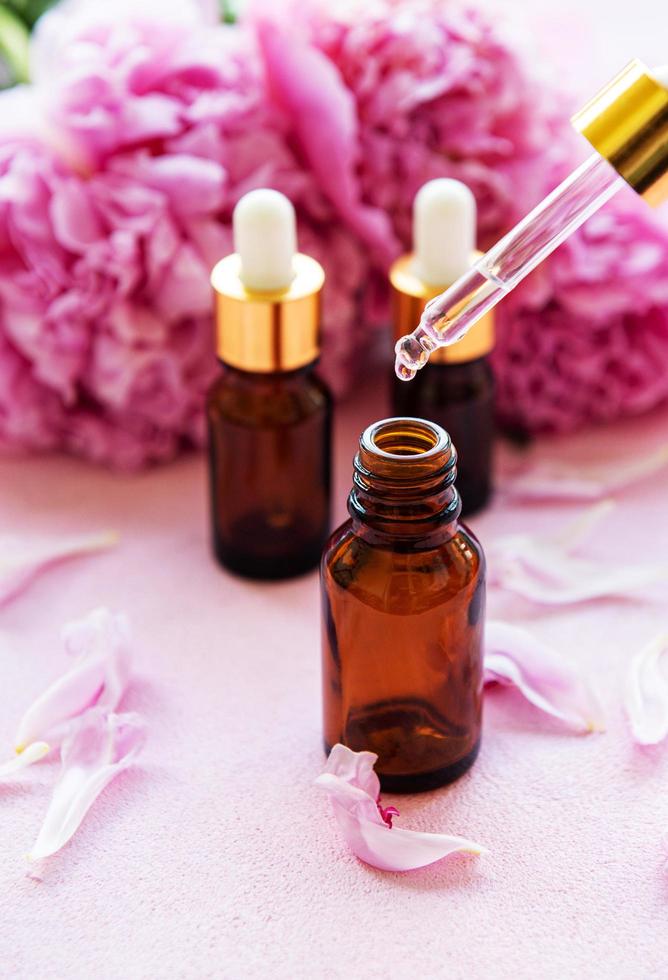 Aromatherapy essentials oils and pink peonies photo