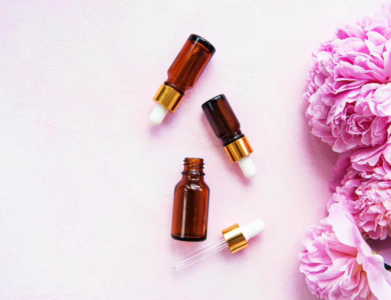 Aromatherapy essentials oils and pink peonies photo